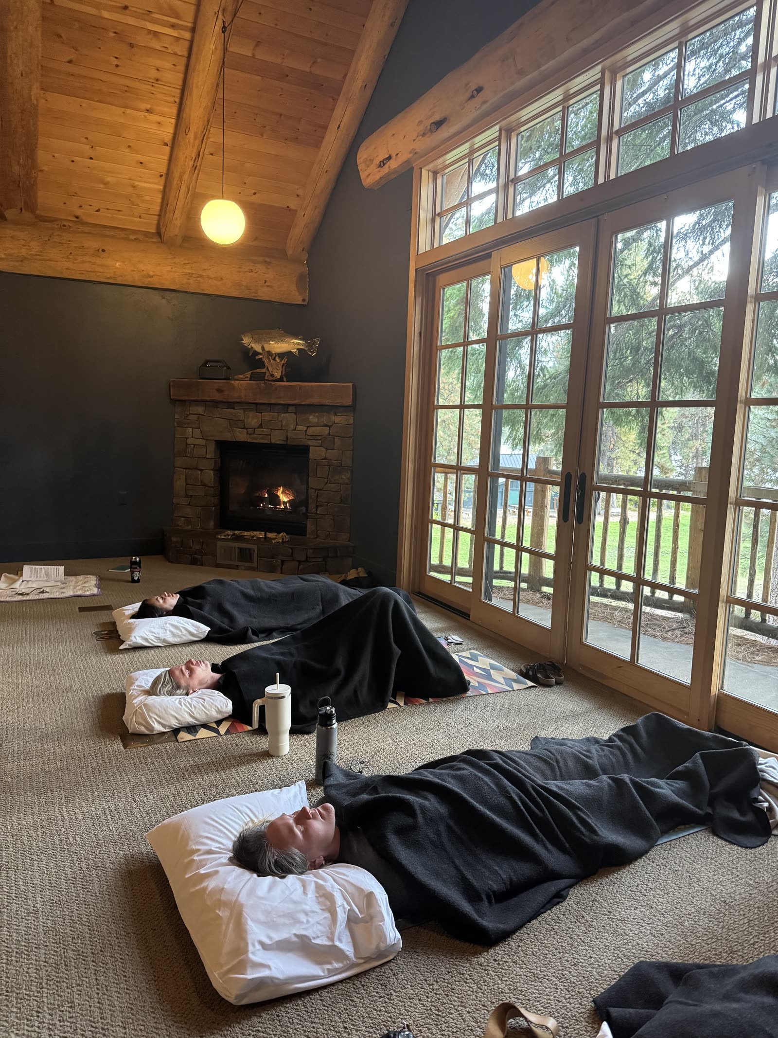 Guests resting under blankets by the lodge fireplace during a session