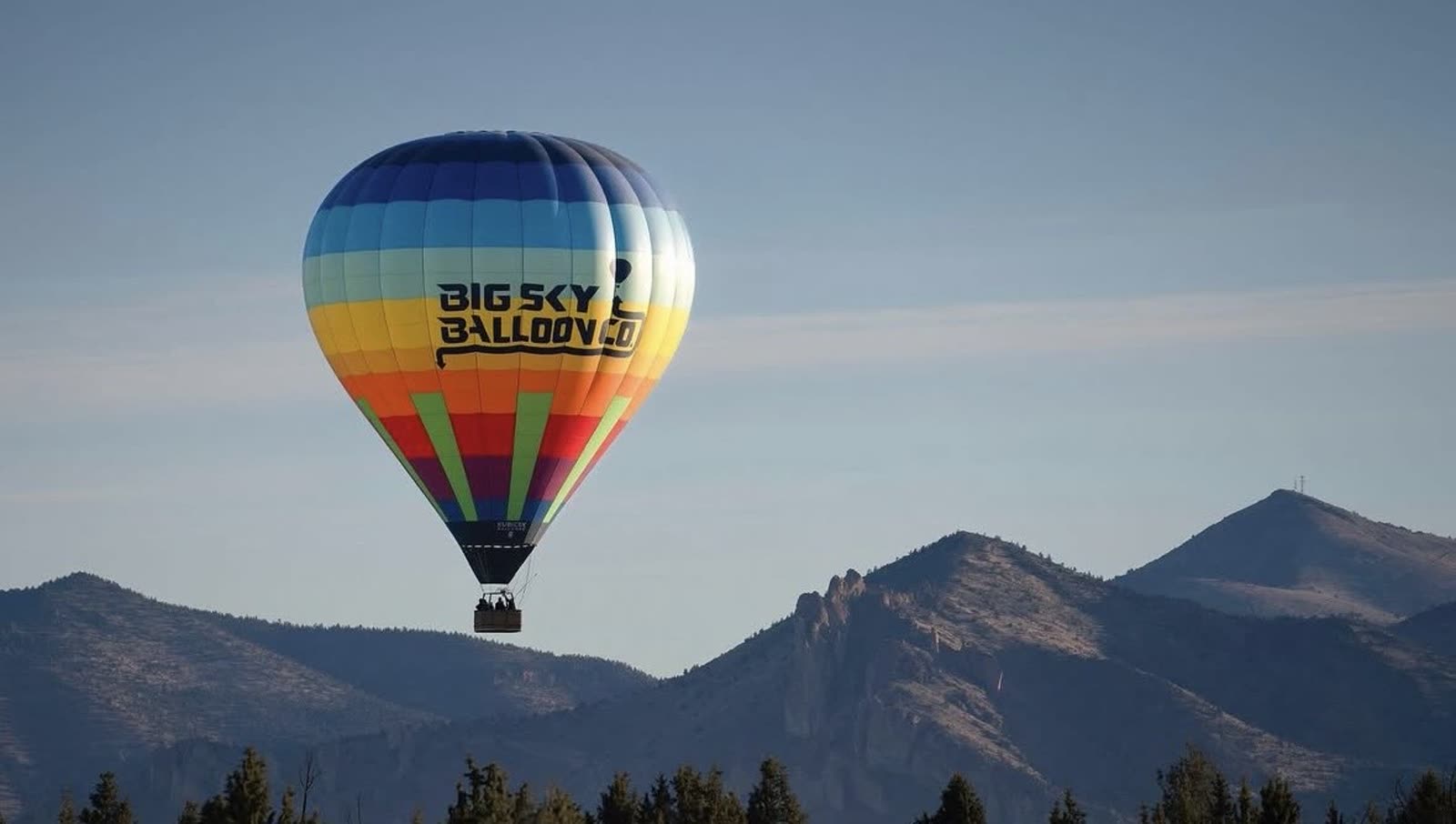 Hot air balloon aloft over the high desert mountains